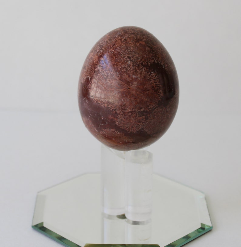 Vintage Brown Marble Stone Egg And Stand With Mirror.
Brown Marble Egg and Lucite Stand and 4-Inch Octagon Mirror. 
The Egg Has a Smooth, High Polish Finish.
The Stand is Clear Lucite.
Egg and Stand Measure 4 Inches.
The Gemstone Egg is 2 3/4 Inches by 2 Inches.
One More Really Nice Egg For your Collection.