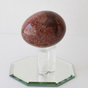 Vintage Brown Marble Stone Egg And Stand With Mirror.
Brown Marble Egg and Lucite Stand and 4-Inch Octagon Mirror. 
The Egg Has a Smooth, High Polish Finish.
The Stand is Clear Lucite.
Egg and Stand Measure 4 Inches.
The Gemstone Egg is 2 3/4 Inches by 2 Inches.
One More Really Nice Egg For your Collection.