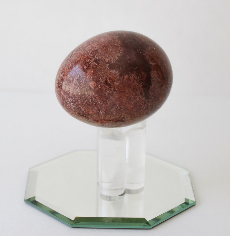 Vintage Brown Marble Stone Egg And Stand With Mirror.
Brown Marble Egg and Lucite Stand and 4-Inch Octagon Mirror. 
The Egg Has a Smooth, High Polish Finish.
The Stand is Clear Lucite.
Egg and Stand Measure 4 Inches.
The Gemstone Egg is 2 3/4 Inches by 2 Inches.
One More Really Nice Egg For your Collection.