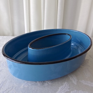 May include: A blue enamel serving dish with a smaller, oval-shaped dish inside. The dish has a black rim.