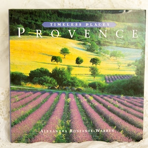 May include: A book cover featuring a scenic landscape of Provence. The cover displays the title "PROVENCE" with the text "TIMELESS PLACES" above it. The image shows fields of lavender and rolling hills under a bright sky. The author's name, Alexandra Bonfante-Warren, is at the bottom.