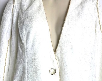 May include: White lace blazer with a gold trim and a single button closure. The blazer has a deep V-neckline and long sleeves.