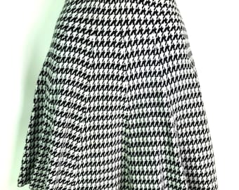 May include: Black and white houndstooth skirt with a flared silhouette. The skirt has a high waist and a scalloped hem.