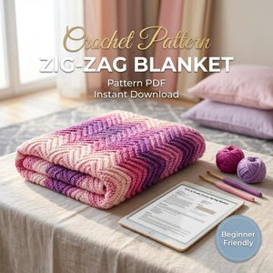 Op de afbeelding: Een gevouwen zigzag gehaakte deken in roze en paarse tinten ligt op een tafel. De tekst "Crochet Pattern ZIG-ZAG BLANKET" is zichtbaar. Een tablet toont een patroon, met bollen wol en haaknaalden ernaast.