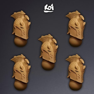 Puede incluir: Cinco cascos de caballero en miniatura de color tostado dispuestos en un patrón, cada uno con una cresta texturizada, una visera puntiaguda con orificios de ventilación y una base de cuello redondeada. La palabra Koi está impresa en blanco.