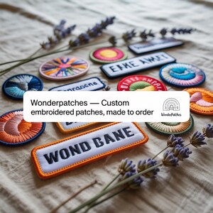 Puede incluir: Una colección de parches bordados personalizados en varias formas y colores, incluyendo círculos y rectángulos. Los parches presentan texto y diseños coloridos, con el texto "ERKE AMER" y "WOND BANE" visibles. También hay ramitas de lavanda.