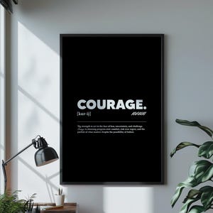 May include: Black framed wall art with the word "COURAGE" in white, along with its pronunciation and definition. The art is displayed on a white wall, next to a window and a potted plant.