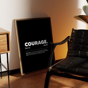 May include: A framed black print with the word "COURAGE" in white, with a definition below. The print leans against a wall next to a wooden side table with a Buddha statue and a black leather chair.