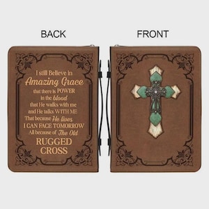 May include: Brown Bible cover with a cross design on the front and text on the back. The front features a green and silver cross. The back has the words "Amazing Grace" and other text in a decorative frame.