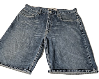 May include: Blue denim shorts with a classic five-pocket design. The shorts have a button and zipper closure, belt loops, and rolled-up cuffs. The denim has a faded wash for a worn look.