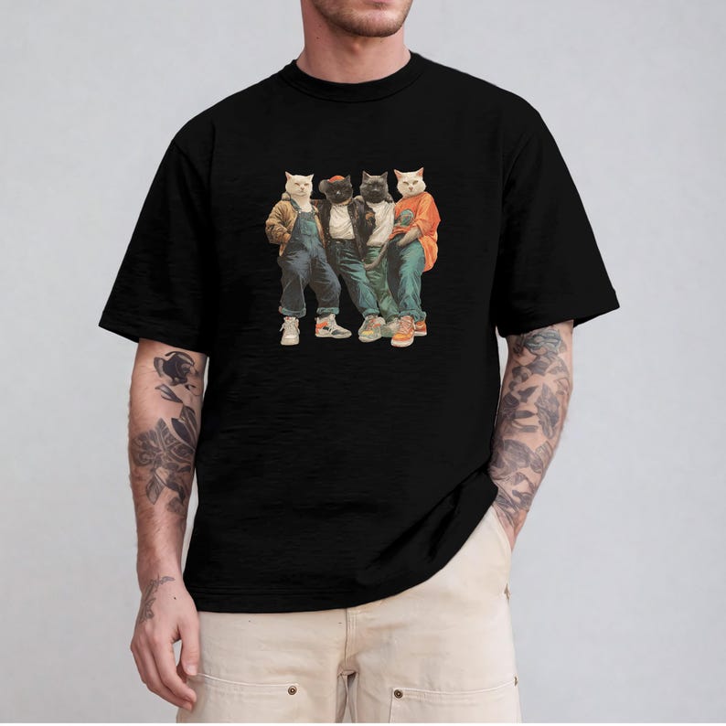 Puede incluir: Camiseta negra con un gr&aacute;fico de cuatro gatos vestidos con ropa urbana. Los gatos llevan monos vaqueros, chaquetas y zapatillas deportivas. La imagen tiene un estilo vintage y de dibujos animados.