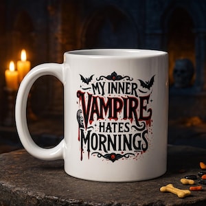 Puede incluir: Taza de cer&aacute;mica blanca con el texto "MY INNER VAMPIRE HATES MORNINGS" en letras g&oacute;ticas rojas y negras. La taza presenta murci&eacute;lagos y gotas de sangre, ideal para Halloween.