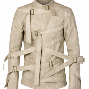 May include: A beige jacket with a textured finish, featuring a high collar and multiple long straps that wrap across the front and sleeves. Each strap is secured with a rectangular brass-toned metal buckle, creating a layered, crisscross design.