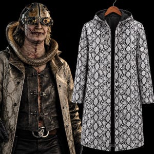 May include: A long-sleeved hooded coat featuring a black and white snakeskin pattern. The coat has a front opening with visible buttons and is displayed on a hanger. The design includes a hood and a consistent reptilian scale print throughout.