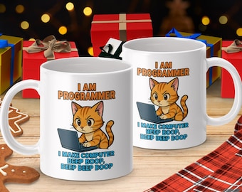 Op de afbeelding: Twee witte keramische mokken met een cartoon kat. De oranje en witte kat zit voor een laptop. De tekst op de mokken luidt "I AM PROGRAMMER" en "I MAKE COMPUTER BEEP BOOP, BEEP BEEP BOOP."