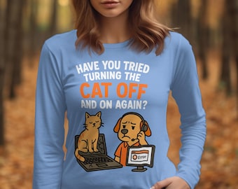 Pode incluir: Camiseta azul clara de manga comprida com o texto "HAVE YOU TRIED TURNING THE CAT OFF AND ON AGAIN?". A camiseta apresenta um gato de desenho animado sentado em um laptop e um cachorro com fones de ouvido olhando para uma tela de computador com uma mensagem de erro.
