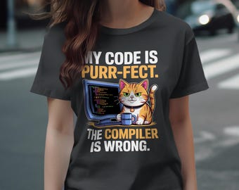 May include: Dark gray t-shirt with a cartoon cat and computer design. The cat is orange and white, holding a mug, and the text reads "MY CODE IS PURR-FECT. THE COMPILER IS WRONG."