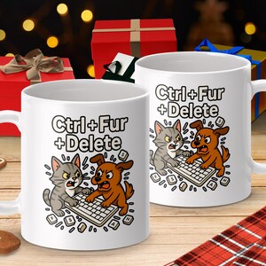 May include: Two white ceramic mugs with the text "Ctrl + Fur + Delete" and a cartoon cat and dog fighting over a keyboard. The mugs are on a wooden surface with holiday decorations in the background.