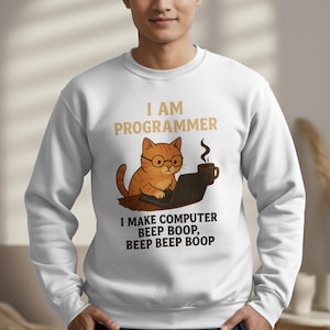 May include: White sweatshirt with a graphic of an orange cat wearing glasses and working on a laptop. The text reads "I AM PROGRAMMER" and "I MAKE COMPUTER BEEP BOOP, BEEP BEEP BOOP". The cat is holding a coffee mug.
