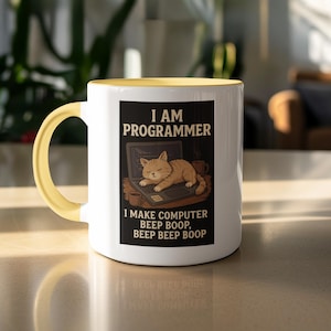 Puede incluir: Taza de cerámica blanca con asa e interior amarillos. La taza presenta un rectángulo negro con el texto "I AM PROGRAMMER" y "I MAKE COMPUTER BEEP BOOP, BEEP BEEP BOOP". Un gato de dibujos animados durmiendo en un portátil.