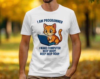 May include: White t-shirt featuring a cartoon orange tabby cat working on a blue laptop. The text above the cat reads "I AM PROGRAMMER", and below it, "I MAKE COMPUTER BEEP BOOP, BEEP BEEP BOOP".