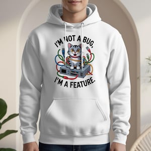 May include: White hoodie featuring a cartoon cat sitting on a computer component, surrounded by colorful wires. The text reads "I'M NOT A BUG, I'M A FEATURE."