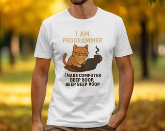 May include: White t-shirt featuring a cartoon cat wearing glasses and working on a laptop. The text above the cat reads "I AM PROGRAMMER", and below it, "I MAKE COMPUTER BEEP BOOP, BEEP BEEP BOOP". A coffee cup is also in the image.
