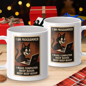 May include: White ceramic mugs featuring a black cat graphic and the text "I AM PROGRAMMER" and "I MAKE COMPUTER BEEP BOOP, BEEP BEEP BOOP". The mugs are on a wooden surface with gift boxes in the background.