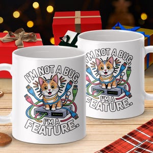 May include: Two white ceramic mugs with a cartoon cat design. The cat is orange and white, surrounded by colorful cables, and the text reads "I'M NOT A BUG, I'M A FEATURE." The mugs are on a wooden surface with holiday decorations.