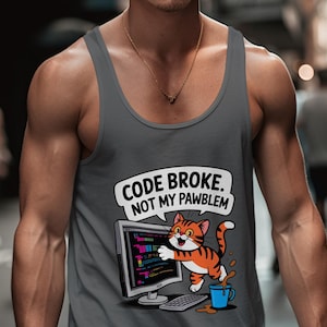 May include: A grey vest top with a cartoon cat interacting with a computer screen. The cat is orange and white, with the text "CODE BROKE, NOT MY PAWBLEM" in a speech bubble. A blue coffee cup is also shown.