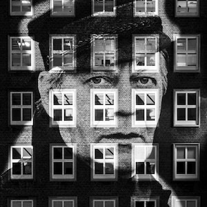 May include: Black and white architectural photograph featuring a brick building with multiple windows. A human face is superimposed over the building, with the windows forming the facial features. The image is a study in contrasts.
