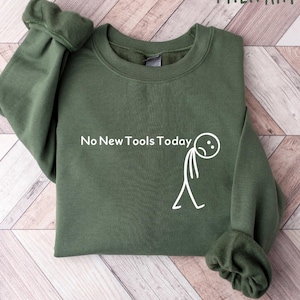 May include: Military green sweatshirt with the text "No New Tools Today" and a stick figure with a sad face. The sweatshirt is made of a soft material and has a crew neck.