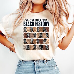 May include: Cream-colored t-shirt with the text "WHAT WE LEARN FROM BLACK HISTORY" above a grid of postage stamp-style portraits of historical figures. The shirt is paired with blue jeans.