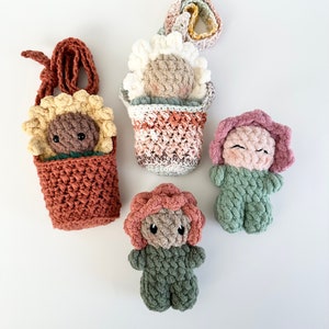 May include: Five crocheted flower-shaped plushies. Two are in flower pots, one is a sunflower, one is a pink flower, and one is a green flower.