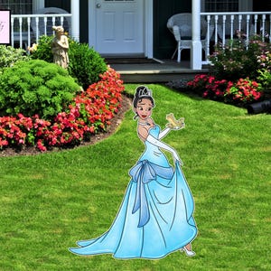 May include: A light blue princess yard decoration. The princess is wearing a light blue gown with a matching bow and long white gloves. She is holding a small frog. The yard decoration is on a green lawn.