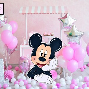 May include: A pink and white party scene with a Mickey Mouse cutout, balloons, and a small cart. The balloons are pink, white, and silver star-shaped. The cart has a pink and white striped awning. The number "1" is visible.