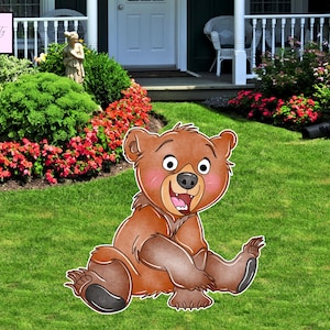 Peut inclure: Un ours brun de dessin animé avec une expression joyeuse, assis sur l'herbe. L'ours a un corps brun clair, des pattes brun foncé et des joues roses. L'ours est dans un jardin avec de l'herbe verte et des fleurs rouges.