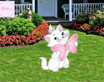 Op de afbeelding: Een witte cartoonkat met een roze strik en een bijpassende strik op haar hoofd. De kat heeft blauwe ogen en staat tegen een achtergrond van groen gras, rode bloemen en een wit huis.