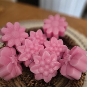 Peut inclure: Un assortiment de fondants parfumés roses en forme de fleurs. Les fondants sont disposés dans un panier tressé. Les fleurs ont des pétales détaillés et une finition lisse et brillante. L'arrière-plan est flou.