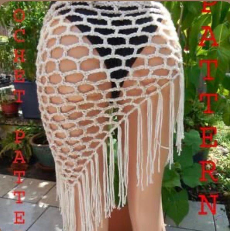 May include: Cream-colored crochet skirt with a honeycomb pattern and fringe detail. The skirt is a wrap style, with a textured design and a bohemian aesthetic. The skirt is a beach cover-up.