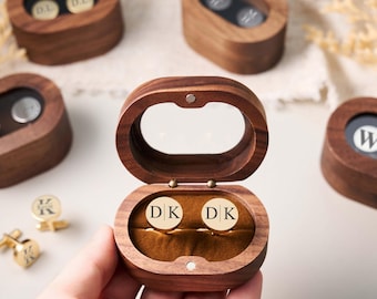 May include: Wooden cufflink boxes with clear oval lids. The boxes are open, revealing gold cufflinks with the initials "DK". Other boxes contain cufflinks with initials. The cufflinks are gold and silver.