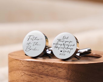 May include: A pair of round silver-toned metal cufflinks. One cufflink features the black text "Father of the Bride" in a script font. The other cufflink displays the text "Dad. Thank you for walking by my side today and always Hailey 07.21.26".