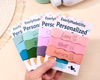 May include: A set of colorful silicone wavy bands for tumblers, each featuring a personalized name and a small animal icon. The bands are displayed on white cards labeled EverlyMadeGifts, showcasing various shades of blue, green, purple, and pink.