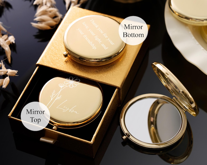 May include: A gold-colored compact mirror with a floral design and the name "Ligba" engraved on the top. The bottom of the mirror has the text "Thank you for your love, your light, and your friendship". The mirror is in a gold box.