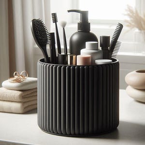 Puede incluir: Un organizador cilíndrico gris oscuro y acanalado contiene varios accesorios de baño. Los artículos incluyen un cepillo para el pelo, un cepillo de dientes, brochas de maquillaje, un peine y un dispensador de jabón. Se ven artículos adicionales, como toallas dobladas y anillos decorativos.