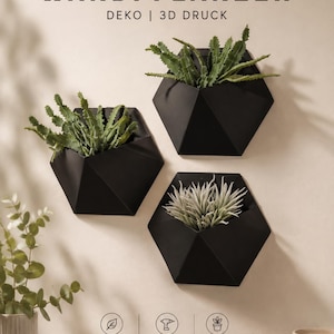 Peut inclure: Trois jardinières murales géométriques noires au design facetté, contenant chacune une plante verte. Le texte WANDPFLANZER DEKO | 3D DRUCK figure en haut, avec des icônes et le texte MODERNES DESIGN, EINFACHE MONTAGE, et FÜR INNEN & AUSSEN en bas.