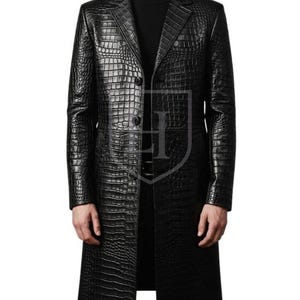 May include: A black, long leather coat with a crocodile skin texture. The coat has a classic lapel collar, a two-button closure, and a long, tailored fit. The coat is worn over a black turtleneck.