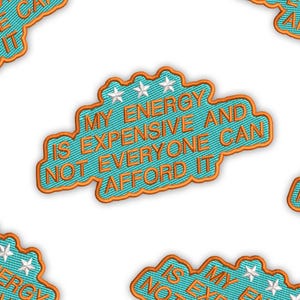 Könnte beinhalten: Wiederholendes Muster aus gestickten Aufnähern. Jeder Aufnäher ist türkis mit orangefarbenem Rand und weißen Sternakzenten. Der Text lautet: "MY ENERGY IS EXPENSIVE AND NOT EVERYONE CAN AFFORD IT".