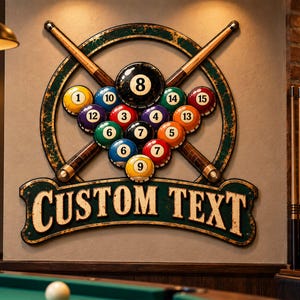 Puede incluir: Un letrero decorativo de pared con un marco circular, dos tacos de billar cruzados y un conjunto de quince bolas de billar numeradas. Debajo del marco hay una pancarta con el texto CUSTOM TEXT en una fuente serif, con un acabado desgastado.