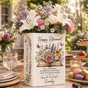 Könnte beinhalten: Eine weiße, buchförmige Keramikvase mit einem Blumenstrauß, dem Text Happy Retirement, A New Chapter Begins und Never underestimate the difference you have made and the lives you have touched. Enjoy the next chapter. Emily.